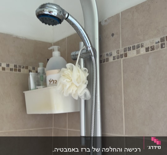 ראש מקלחת ומדף עם מוצרי רחצה